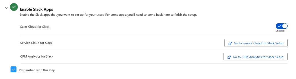 Screenshot of the "Enable Slack Apps" setup step in Salesforce, showing Sales Cloud for Slack toggled on (Enabled), with buttons to navigate to separate setup pages for Service Cloud for Slack and CRM Analytics for Slack. A checked checkbox reads "I'm finished with this step."
